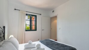 Een hotelkamer met een bed, twee opgerolde handdoeken, een raam met uitzicht en een deur.