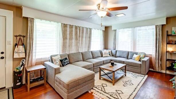 A living room with a sectional sofa, a coffee table, and a ceiling fan. - Hale Leilani - Adventure Awaits (Hilo)