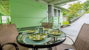 A covered outdoor dining area with green walls and a staircase leading to a building. - Hale Leilani - Adventure Awaits (Hilo)