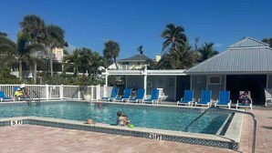 A swimming pool with blue chairs and a covered area. - Captiva home- steps from the beach, pool, restaurants and boat dock (Captiva)