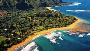 Paisagem costeira com praia, oceano e montanhas ao fundo.