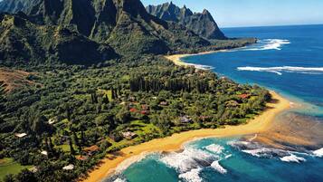 A coastal landscape with a beach, ocean, and mountainous backdrop.