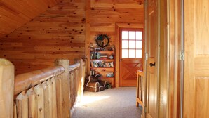 A wooden interior with a sloped ceiling, a bookshelf, a door, and a small dog bed. - Hang out with Moose! Log Cabin near RMNP/Columbine Lake (Grand Lake)