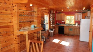 A wooden cabin kitchen with a bar area, wooden cabinets, and a tiled floor. - Hang out with Moose! Log Cabin near RMNP/Columbine Lake (Grand Lake)