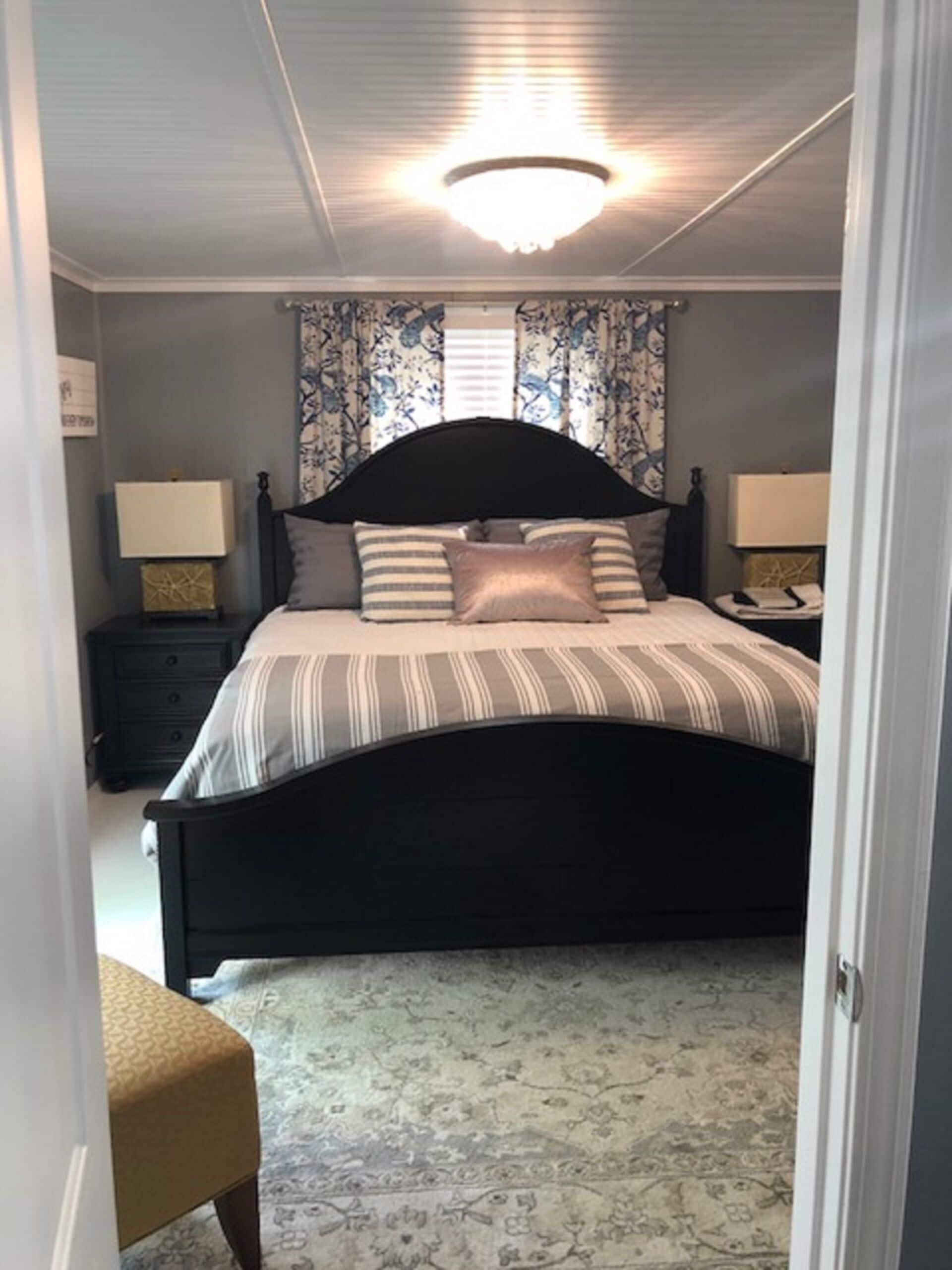 Une chambre à coucher avec un grand lit, deux tables de chevet avec des lampes, une chaise et un tapis à motifs.