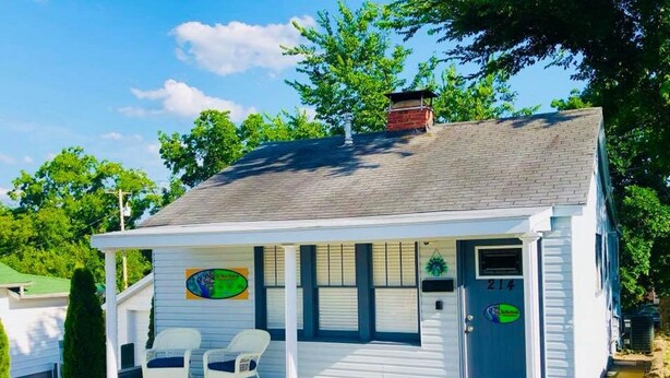 A small, single-story building with a porch, two rocking chairs, and a door marked with the number 214. - Walk to Downtown/The Landing! Beautiful cottage, cozy private hot tub! (Branson)