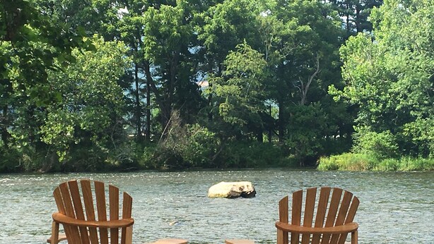 Two wooden Adirondack chairs facing a river with a large rock in the middle. - Fisherman's Dream! Directly on the beautiful Watauga River!  Walk in access! (Elizabethton)