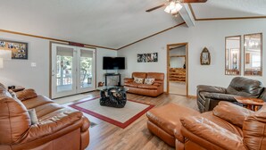 A spacious living room with leather sofas, a glass coffee table, a ceiling fan, and a flat-screen TV. - Fisherman's Dream! Directly on the beautiful Watauga River!  Walk in access! (Elizabethton)