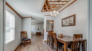 A dining area with a wooden table and chairs, a chandelier, and framed pictures on the wall. - Fisherman's Dream! Directly on the beautiful Watauga River!  Walk in access! (Elizabethton)