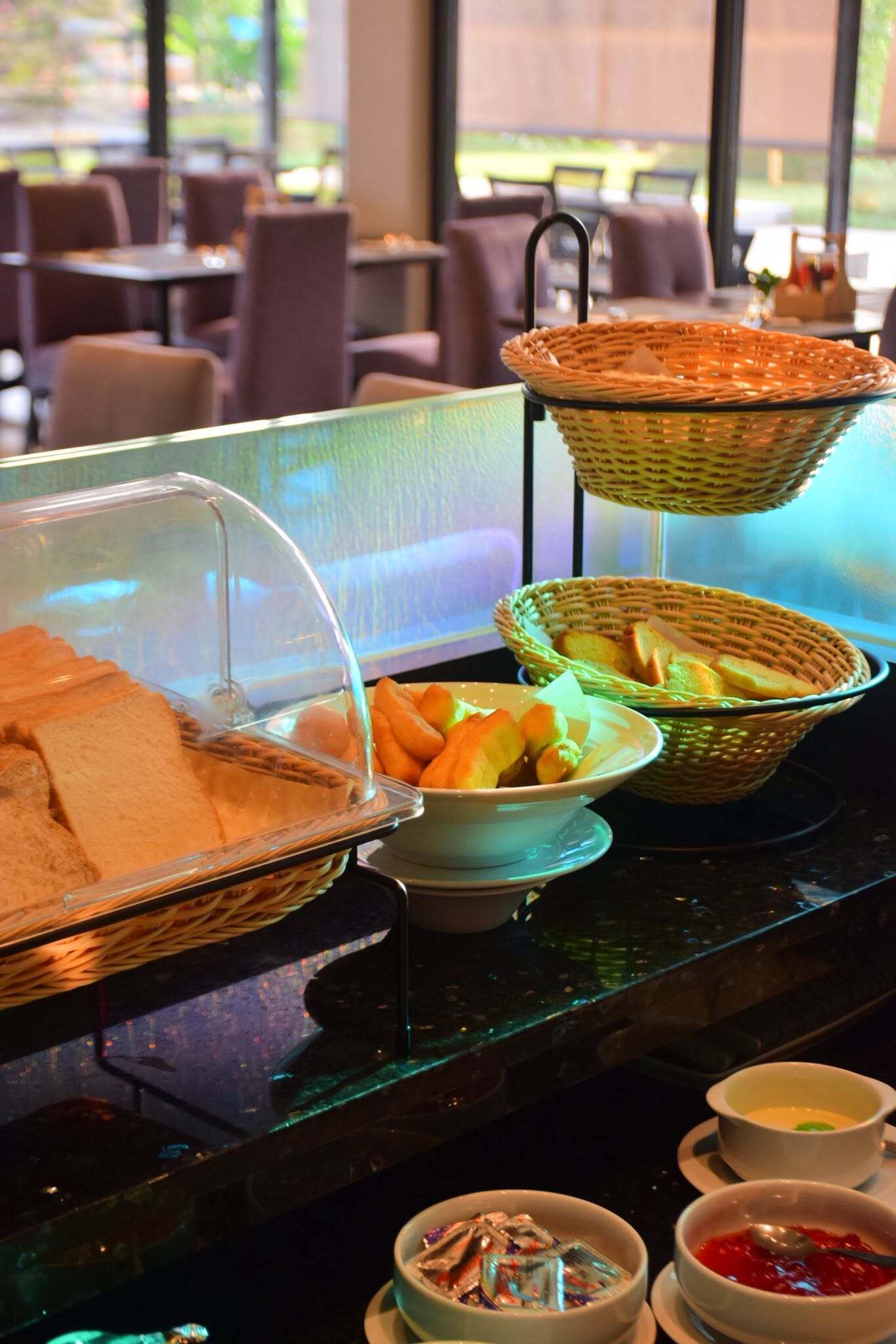 A buffet setup with bread, pastries, and bowls of food on a table.