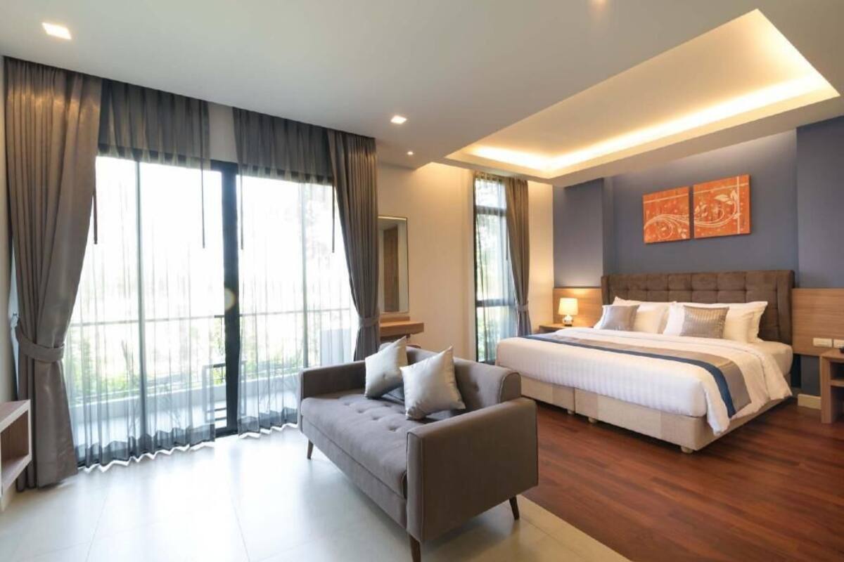 Een moderne slaapkamer met een groot bed, een bank en een nachtkastje.