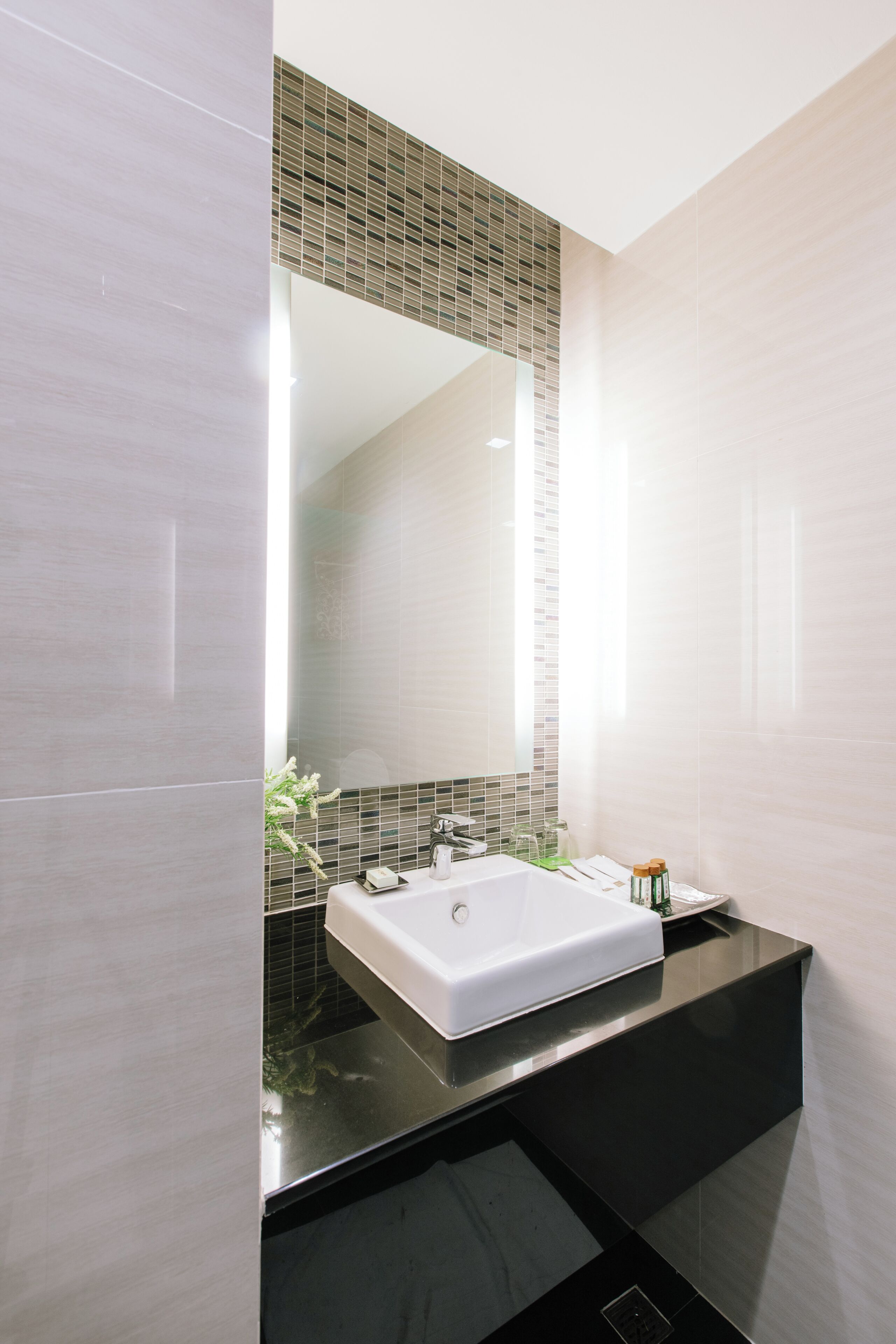 A modern bathroom with a large mirror, a white sink, and a black countertop.