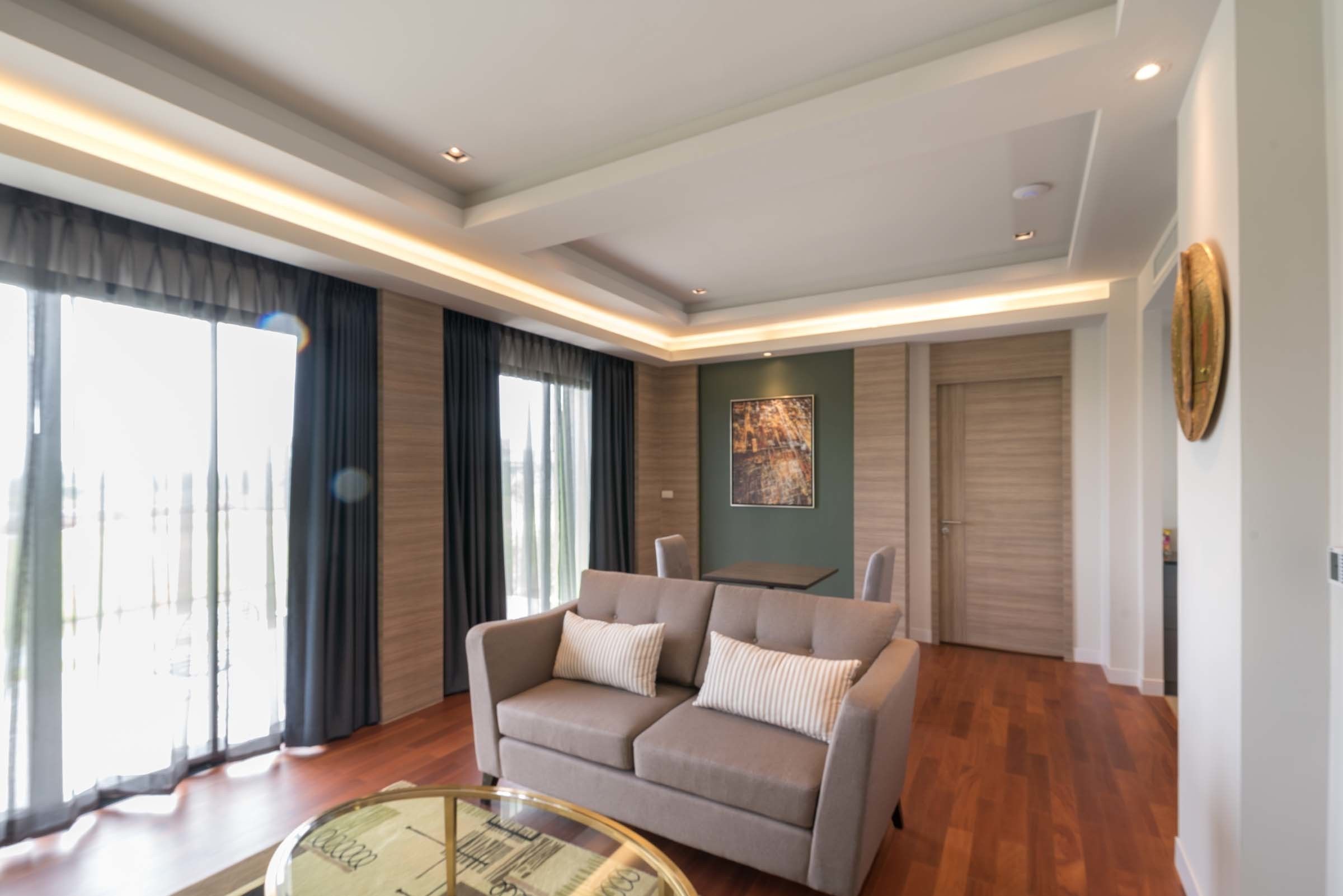 A modern living room with a sofa, a glass coffee table, and a painting on the wall.