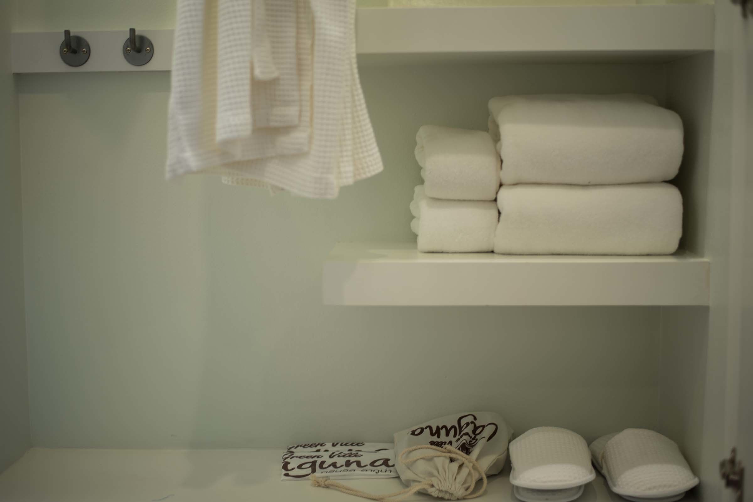 Un baño con una repisa que sostiene toallas dobladas y un par de pantuflas.