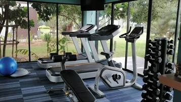 A gym with exercise equipment, a bench, and a blue exercise ball.