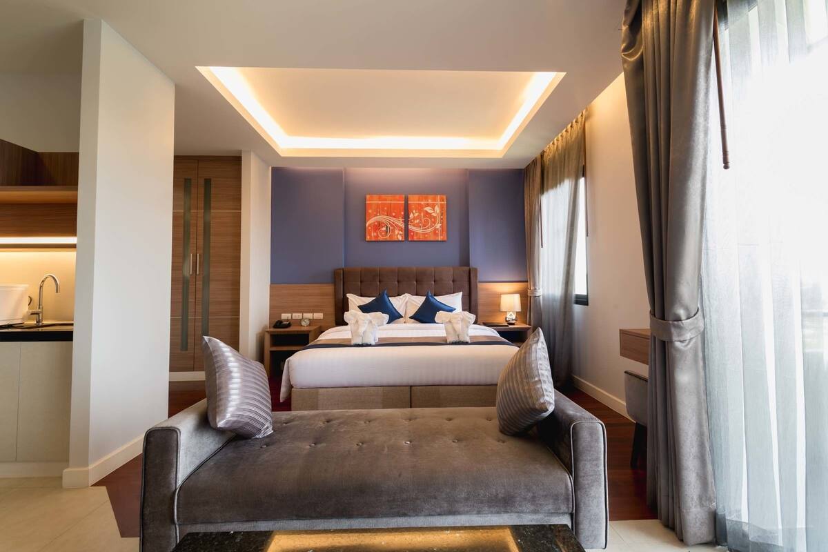 Een moderne hotelkamer met een groot bed, een sofa, een bureau en een badkamer.