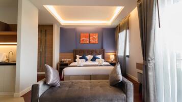 A modern hotel room with a large bed, a sofa, a desk, and a bathroom.