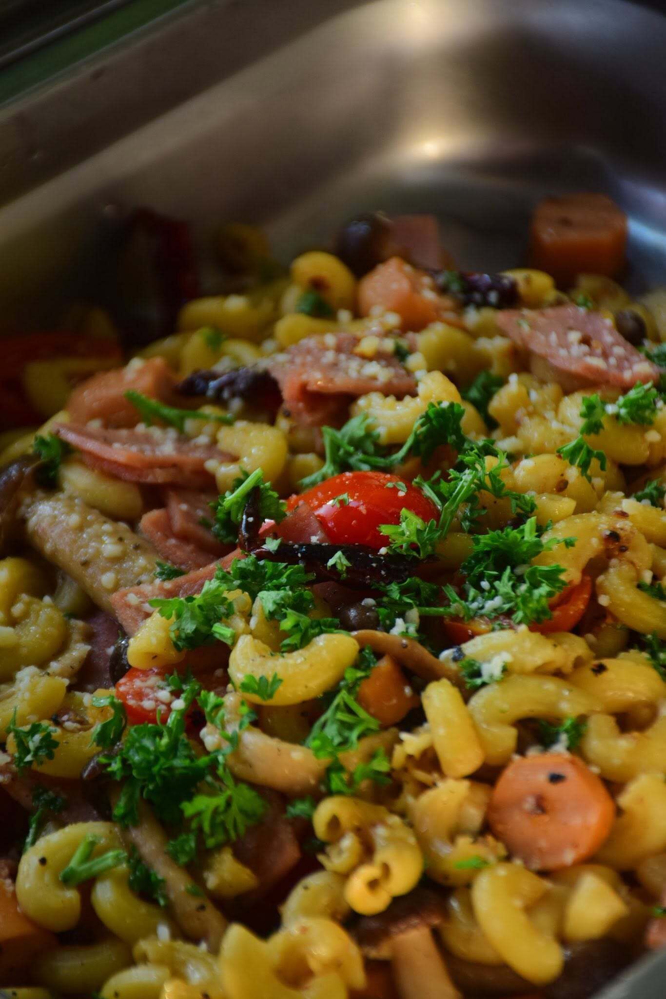 A close-up of a pasta dish with various vegetables and herbs.