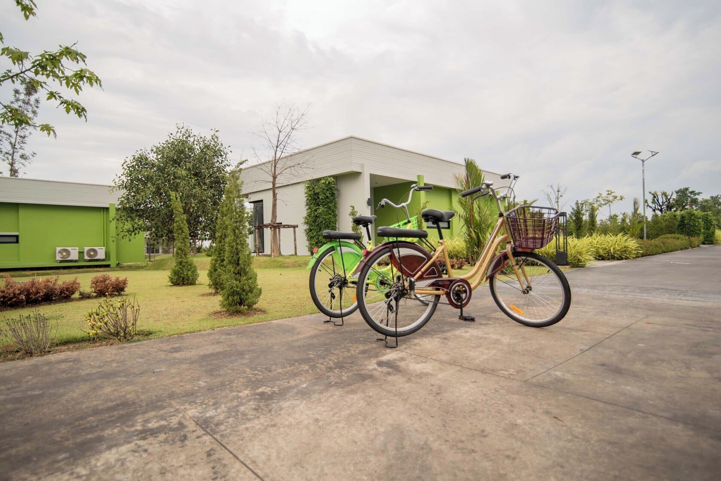 A bicycle parked on a concrete path in front of a building with a green exterior.