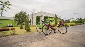 A bicycle parked on a concrete path in front of a building with a green exterior.