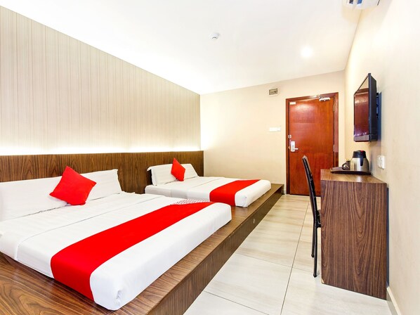 A hotel room with two beds, a wooden headboard, a small desk with a coffee maker, and a TV mounted on the wall. - Hotel O 340 Comfort Hotel (Klang)