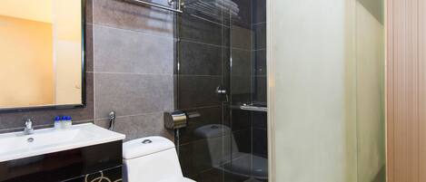 A modern bathroom with a glass shower enclosure, a white toilet, and a sink with a mirror above it.