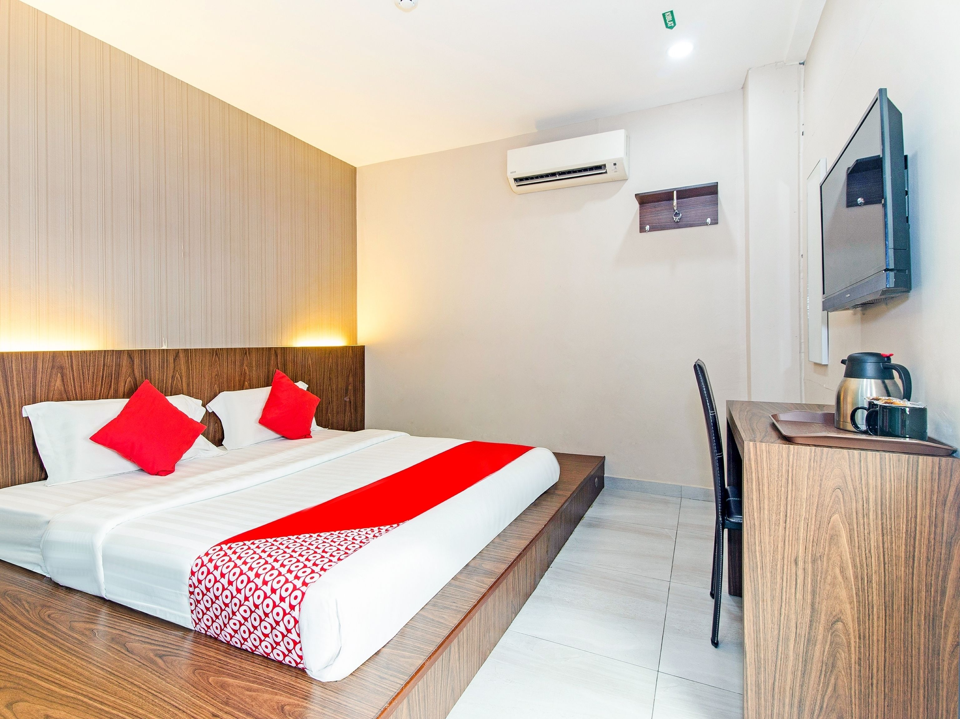 Una habitación de hotel con cama, escritorio, aire acondicionado y espejo.