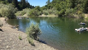 Un río tranquilo con gente en balsas inflables, rodeado de abundante vegetación y árboles.