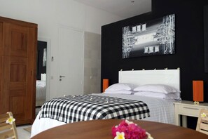 Une chambre à coucher comprenant un lit, une armoire en bois, une table de chevet avec une lampe et une œuvre d’art accrochée au mur.