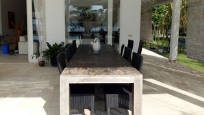 A modern dining area with a long table, black chairs, and a white vase centerpiece. - Villa Cymopoleia (Seririt)