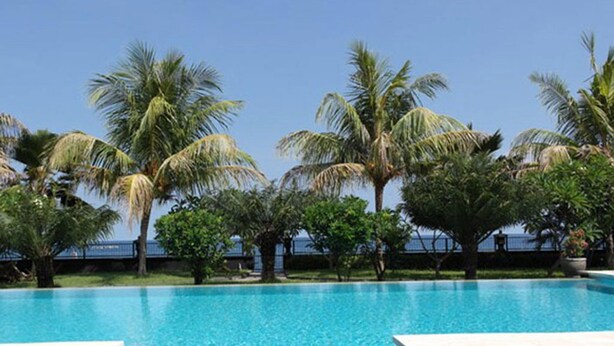 A clear blue pool surrounded by palm trees and a view of the ocean. - Villa Cymopoleia (Seririt)
