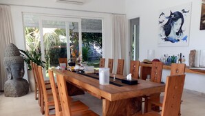 A dining area with a wooden table and chairs, a Buddha statue, and a painting on the wall. - Villa Cymopoleia (Seririt)