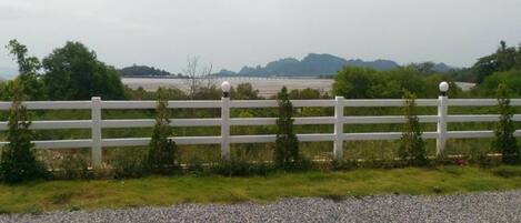 A white fence with evenly spaced posts and spherical lights, leading to a gravel path.