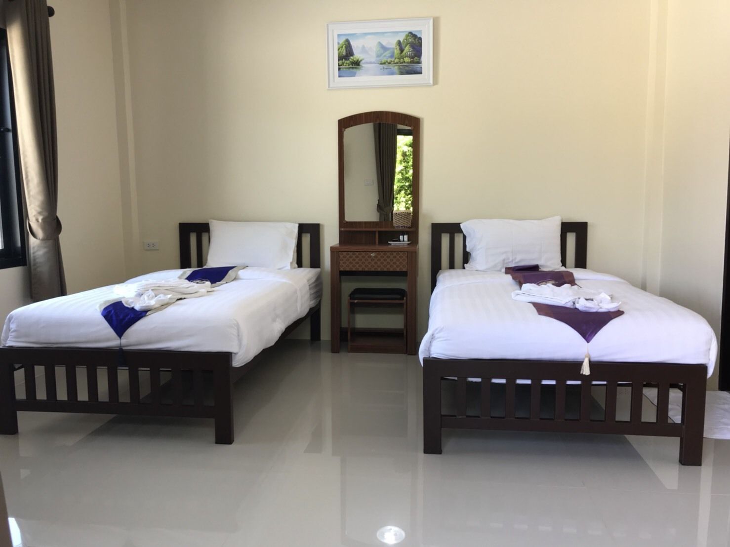 Habitación de hotel con dos camas, un escritorio pequeño y un espejo.