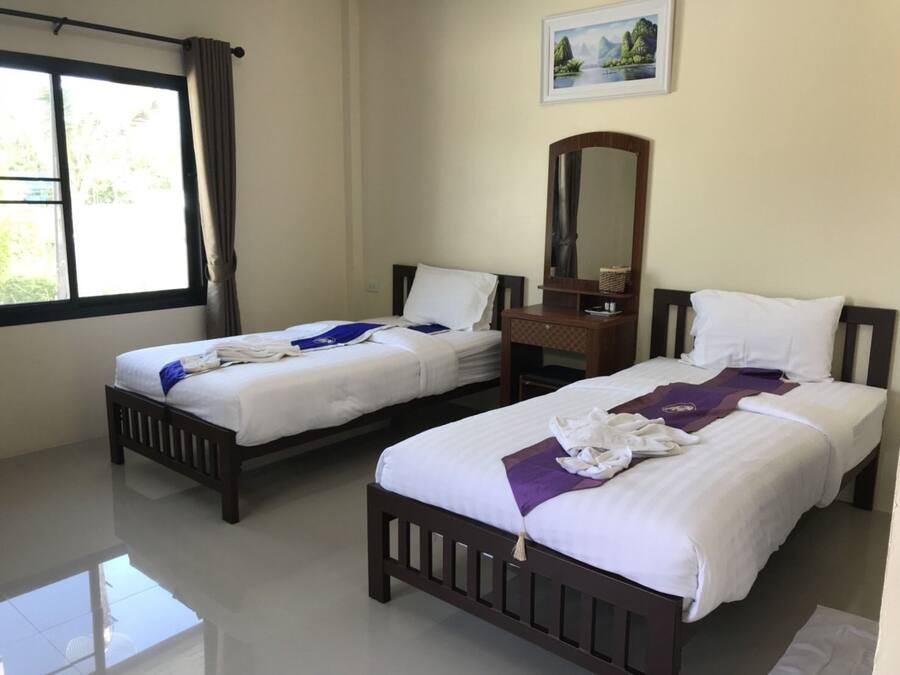 A hotel room with two beds, a wooden dresser, a mirror, and a window with curtains.