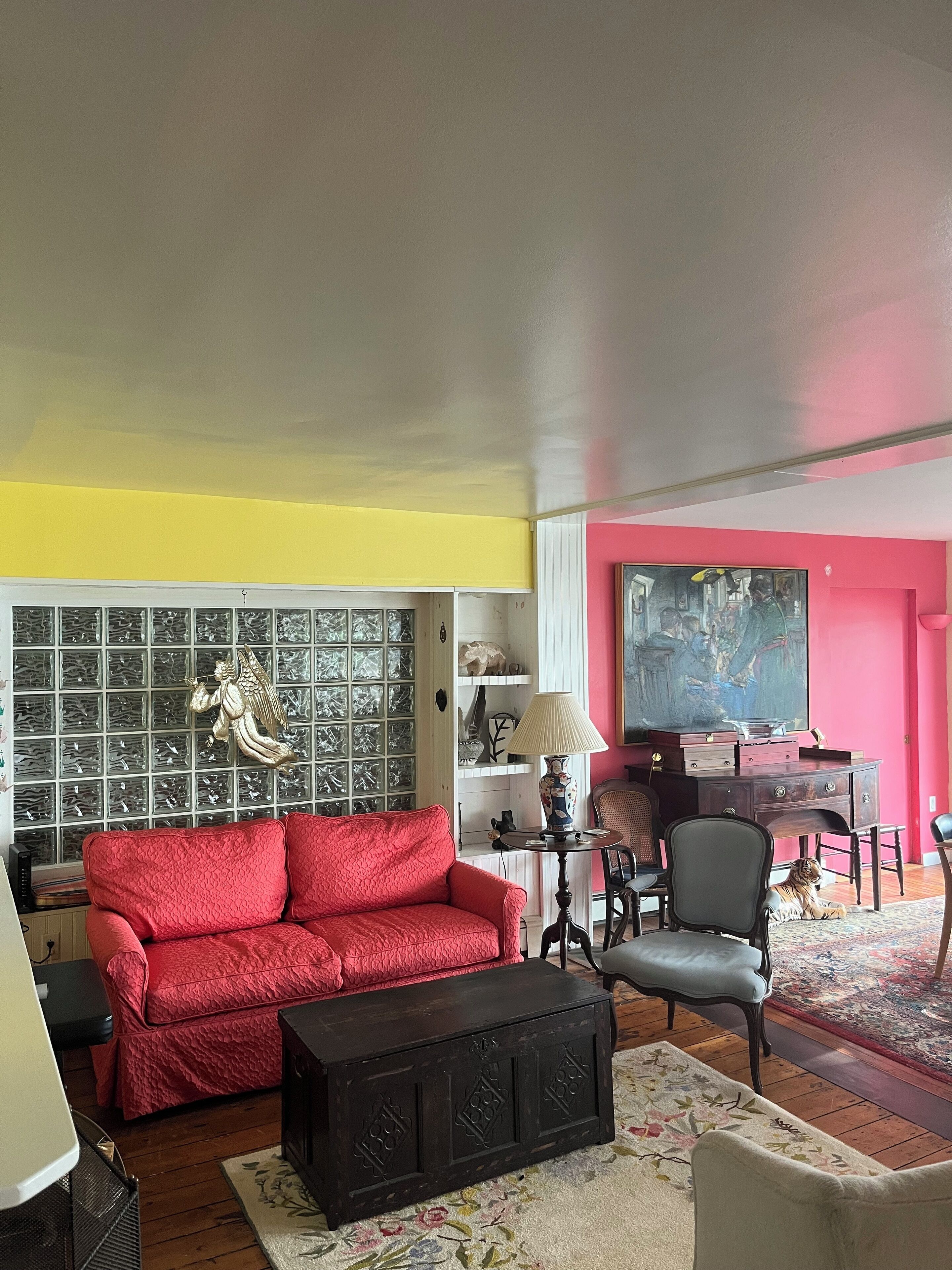 A living room with a red sofa, a black cabinet, a wooden coffee table, and a large painting on the wall.