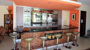 Una cocina con salpicadero de ladrillo, encimera negra y tres taburetes de bar.