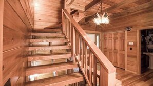 A wooden staircase with a railing, a chandelier, and a garage door. - Ten Mile Cabin Sleeps 16! Best Deal on AirBNB (Ten Mile)