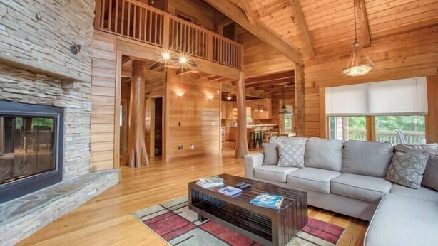 A spacious living area with a fireplace, a sofa, a coffee table, and a balcony. - Ten Mile Cabin Sleeps 16! Best Deal on AirBNB (Ten Mile)