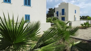 Un bâtiment blanc avec des volets bleus et un balcon, entouré de palmiers.