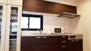 Una cucina compatta con mobili in legno scuro, un forno a microonde integrato e una finestra sopra il lavello.