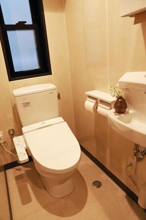 A small bathroom with a toilet, a sink, and a window. - Hostel Taichi-House (Osaka)