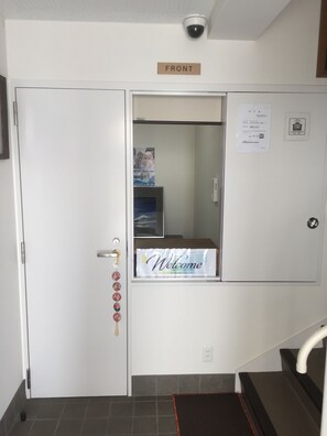A hotel entrance with a 'Welcome' sign, a 'Front' sign, and a security camera. - Hostel Taichi-House (Osaka)
