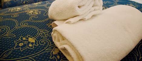 A hotel room with two beds, each with a blue patterned bedspread and white linens.