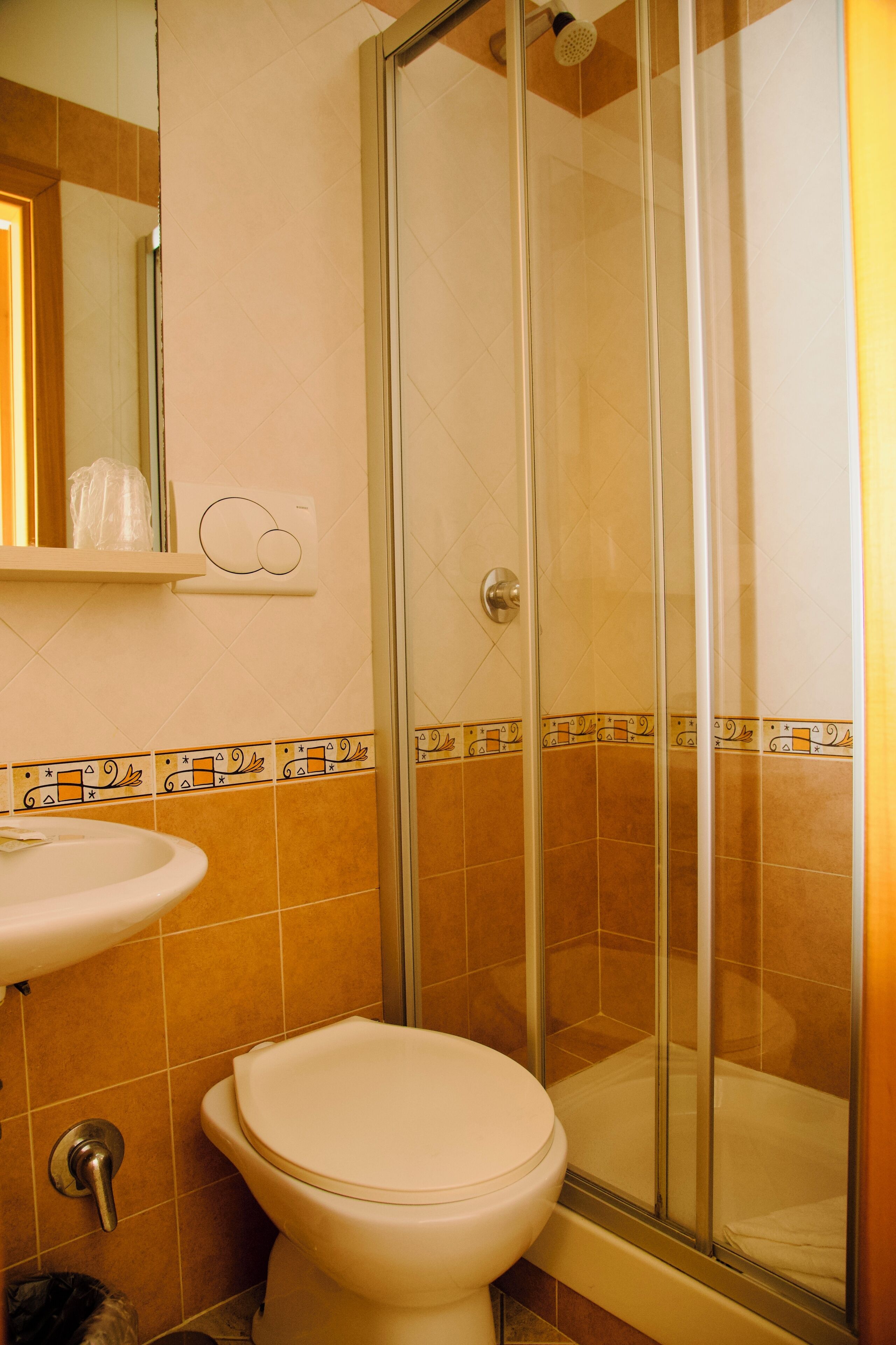 A bathroom with a toilet, sink, and shower enclosure.