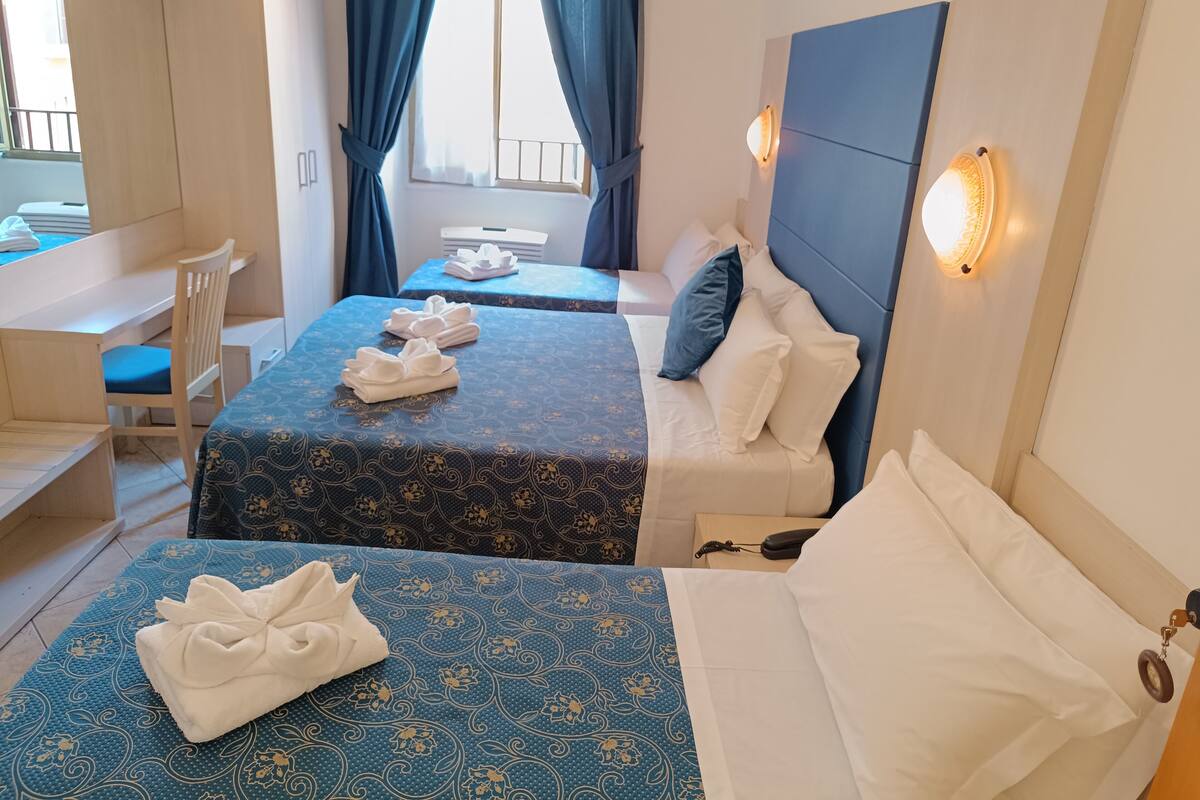 A hotel room with two beds, a desk, and a chair.