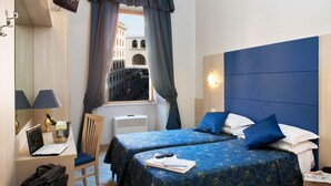 Une chambre d’hôtel avec deux lits, un bureau avec un ordinateur portable, une chaise, une télévision et une fenêtre avec des rideaux.