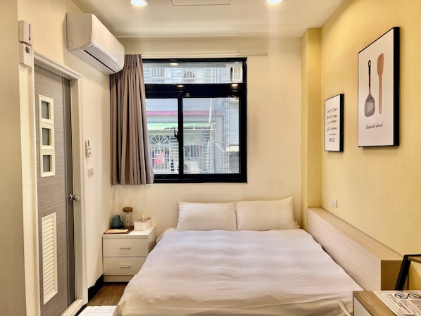 A bedroom with a bed, a nightstand, a window with curtains, and wall-mounted air conditioning. - Taipei Yes hostel (New Taipei City)