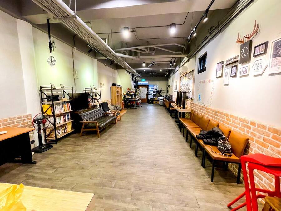 A spacious indoor area with a long wooden table, several chairs, and a sofa. There are bookshelves and a television on the left side.
