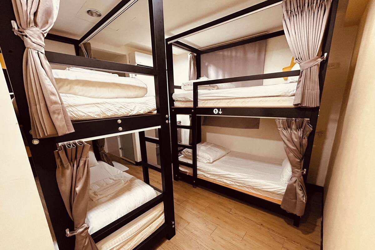 Quarto com beliches, piso de madeira e unidade de ar condicionado visível.